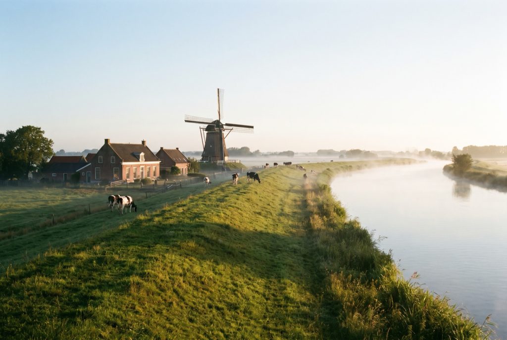 Digue le long de la Lek près d’Utrecht, avec un moulin au lever du soleil